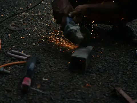Angle grinder cutting a steel section with sparks