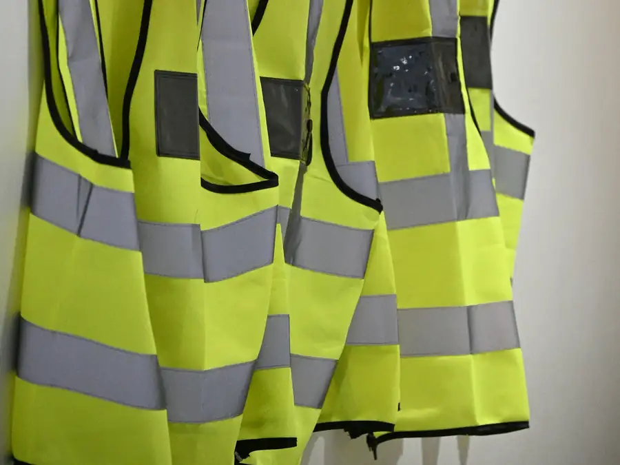High-visibility vests and helmets hanging on a wall