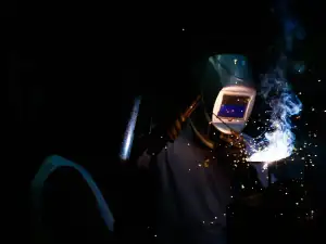Welder wearing a welding helmet, arc lit