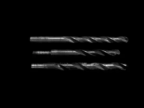 Three twist drill bits on a dark background